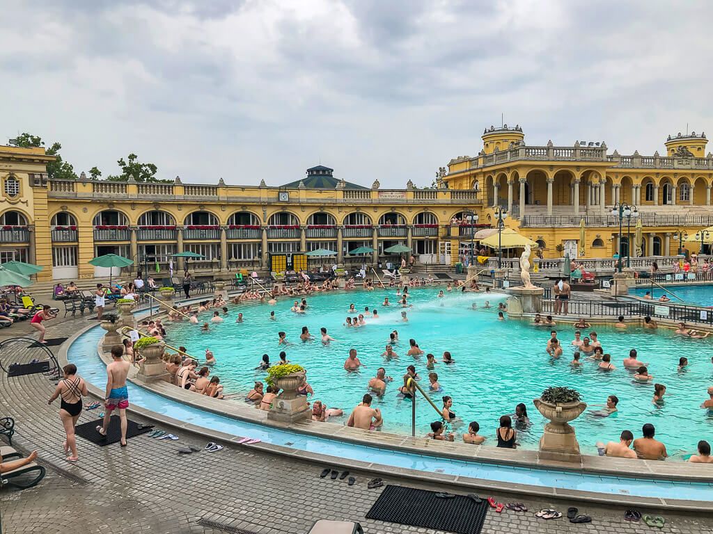 tourists enjoying szechenyi thermal baths outdoor pool
