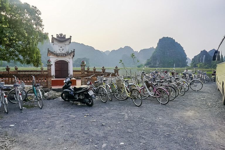 Line of bicycles with a few mopeds parked at the entrance to Mua Cave viewpoint