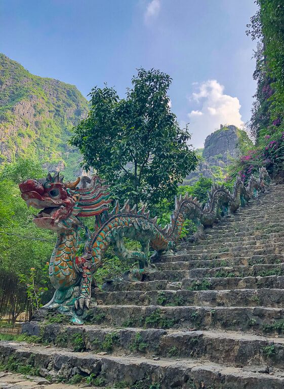 A colorful stone dragon at the start of stone staircase leading to the Mua Cave viewpoints