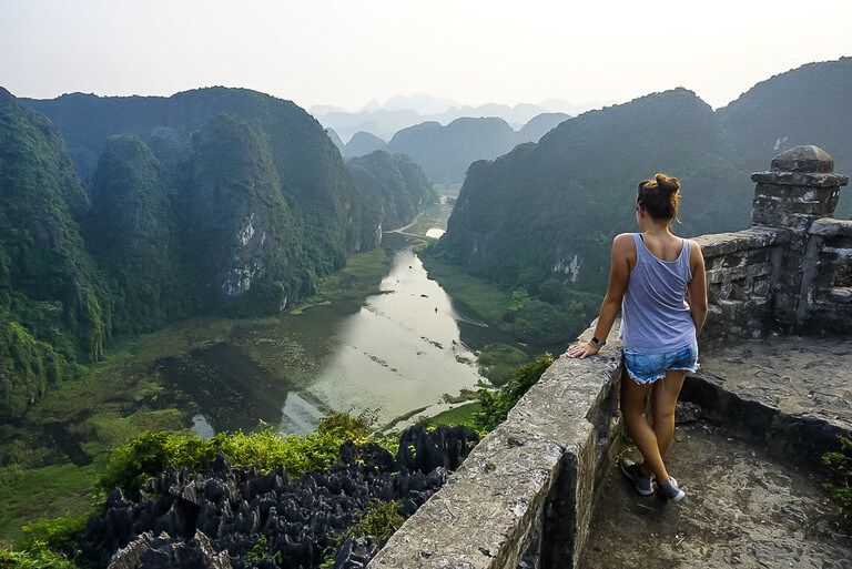 Woman looking out across the beautiful scenery as a river cuts through massive limestone karsts