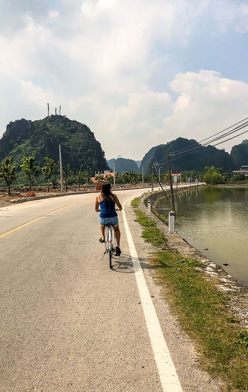 Woman cycling to Bich Dong Pagoda along a quiet road