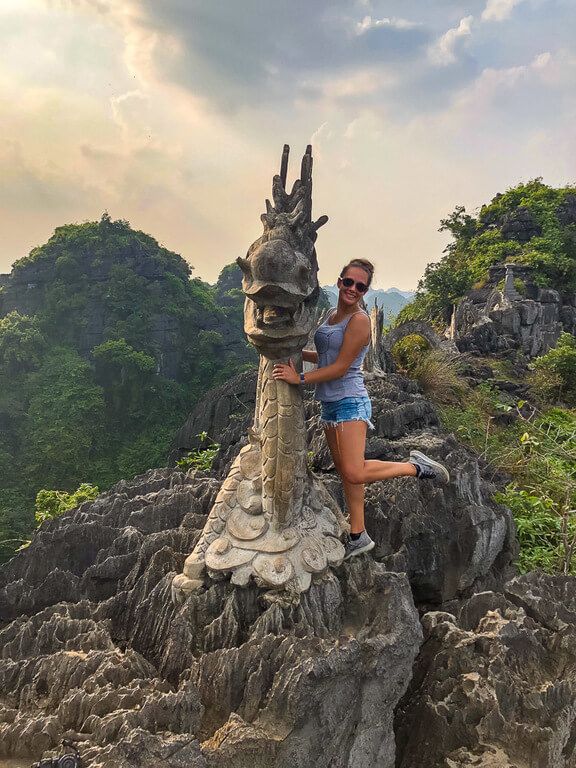 Woman posing for a photo on top of the stone dragon at Mua Cave viewpoint