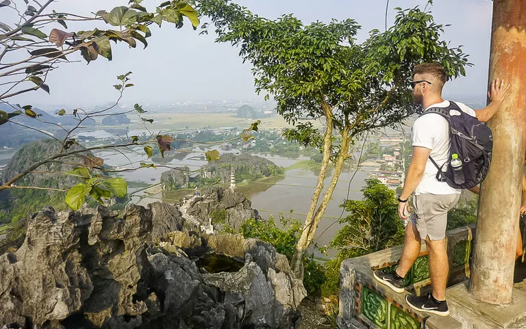 Man enjoying the view at the summit of Mua Cave with rice paddies in the background