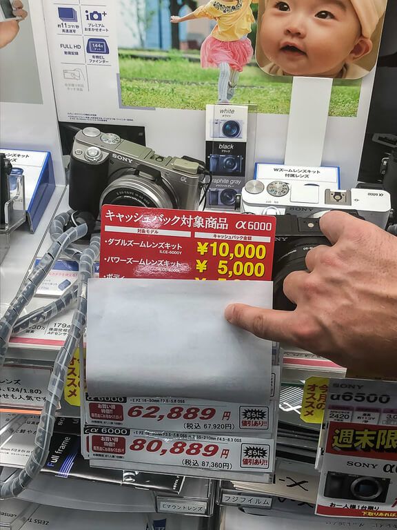 Man holding paper up to reveal price of camera in a tokyo store