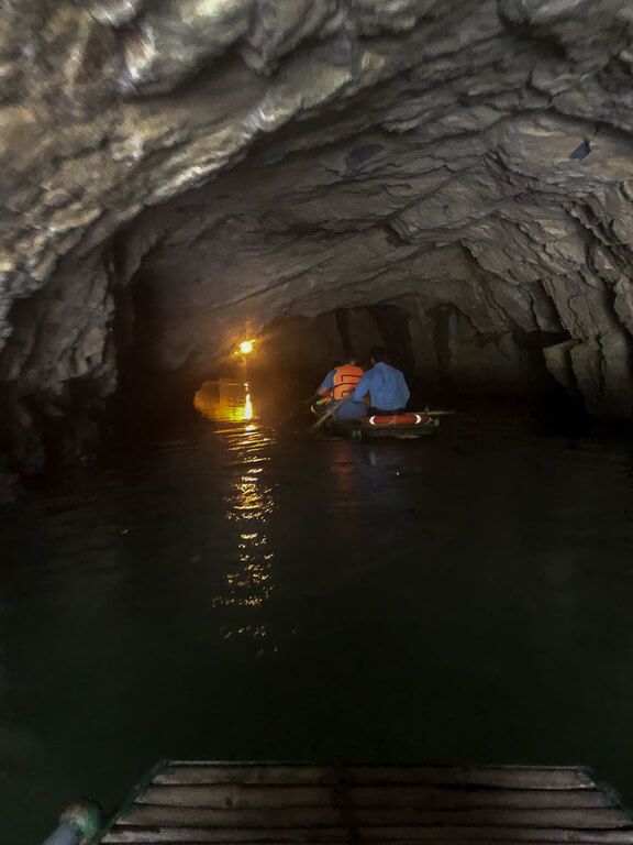 boat floating through dark cave with light for navigation