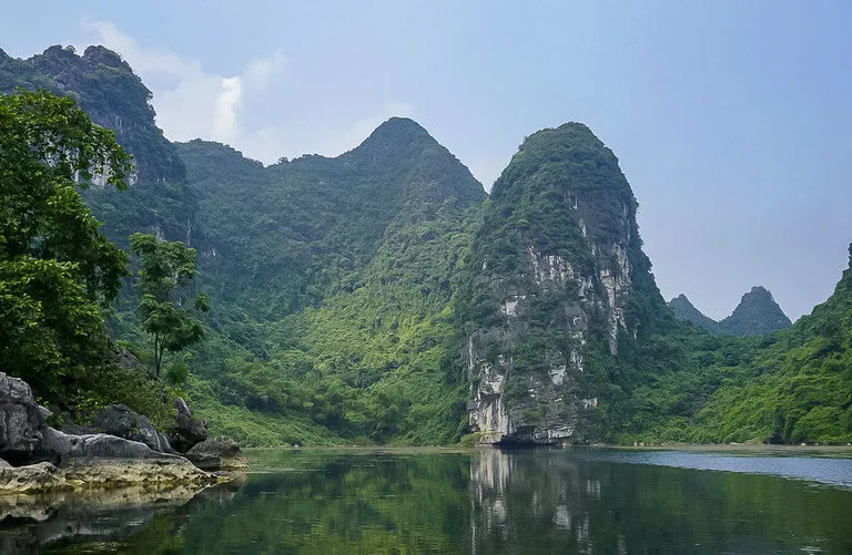 still water with limestone rock and cave at its bottom