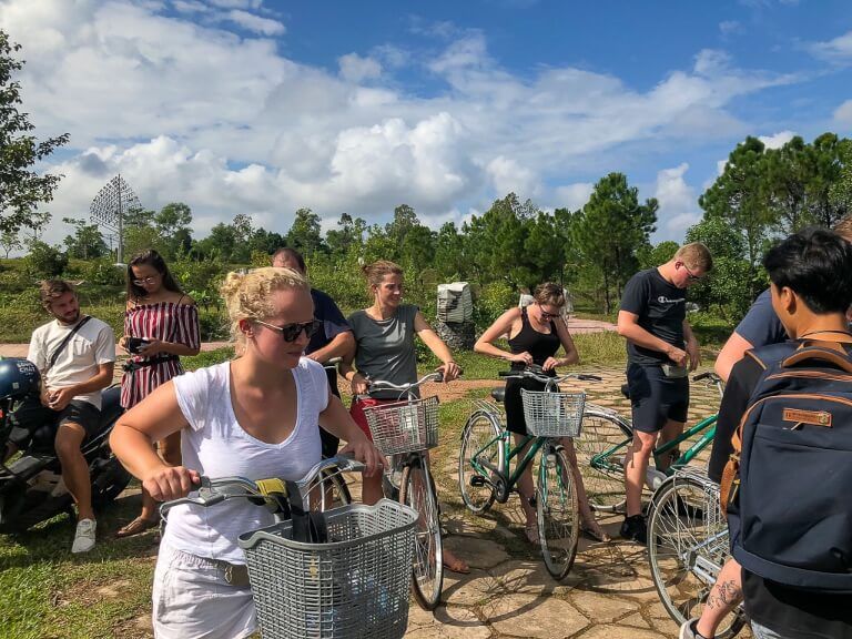 group of backpackers on bikes paying guide into abandoned water park hue