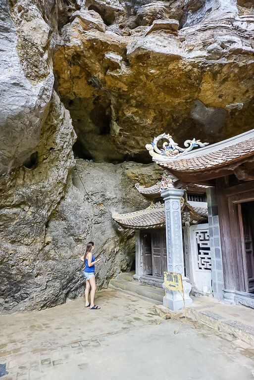 Woman stood at the side of Trung Pagoda about to enter a tight space into the cave