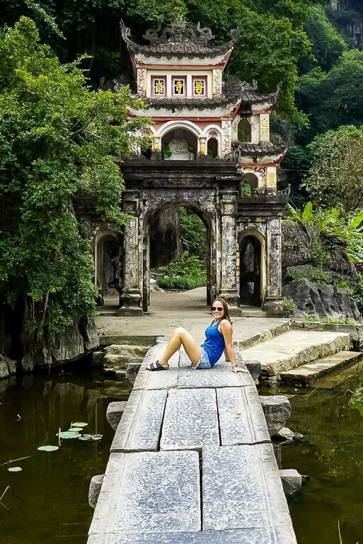 Woman sitting on the bridge in front of Bich Dong pagoda entrance Tam Coc