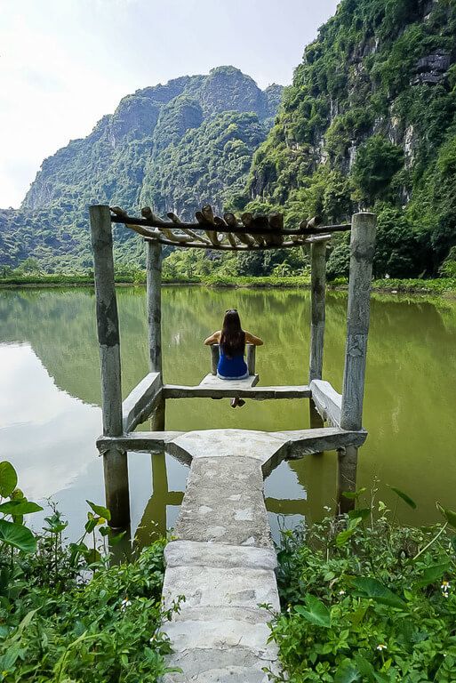 Woman sitting on a wooden dock overlooking a green lake