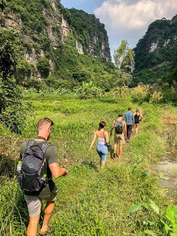 Man with other tourists walking through field to cave