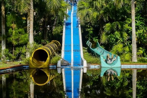 mark pretending to slide into a pool on a green water slide