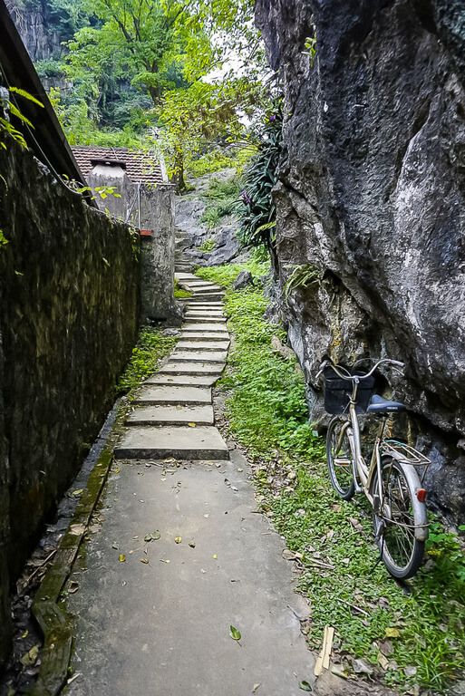 A narrow path on the Bich Dong grounds wall with a bicycle parked to the left