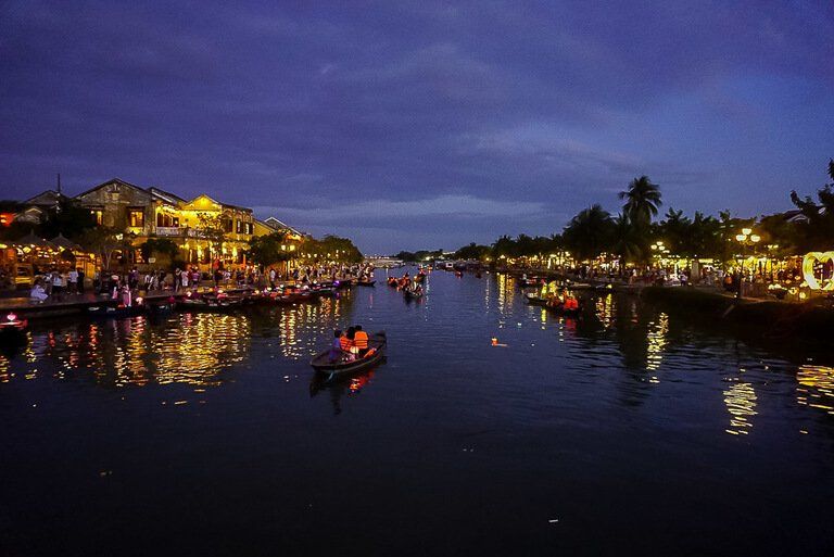 Boats on Thu Bon River in Hoi An Vietnam at night building lit up