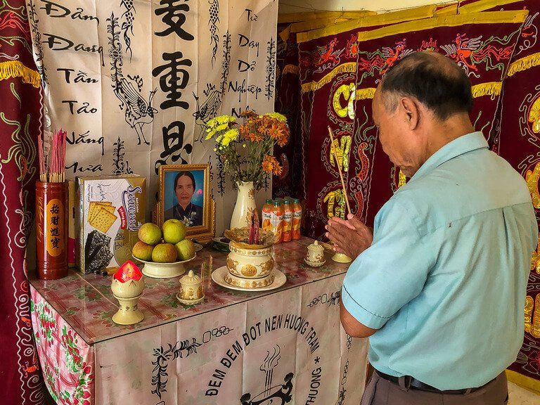 Vietnamese man praying to shrine in his home