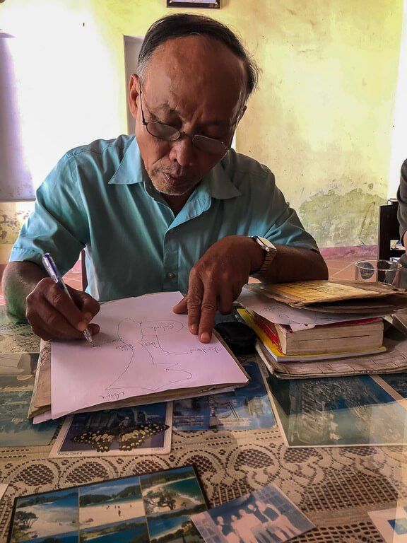 Vietnamese man writing on pink paper in his house private Hoi An tour