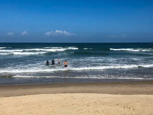 People in sea waving at a swimmer in Vietnam