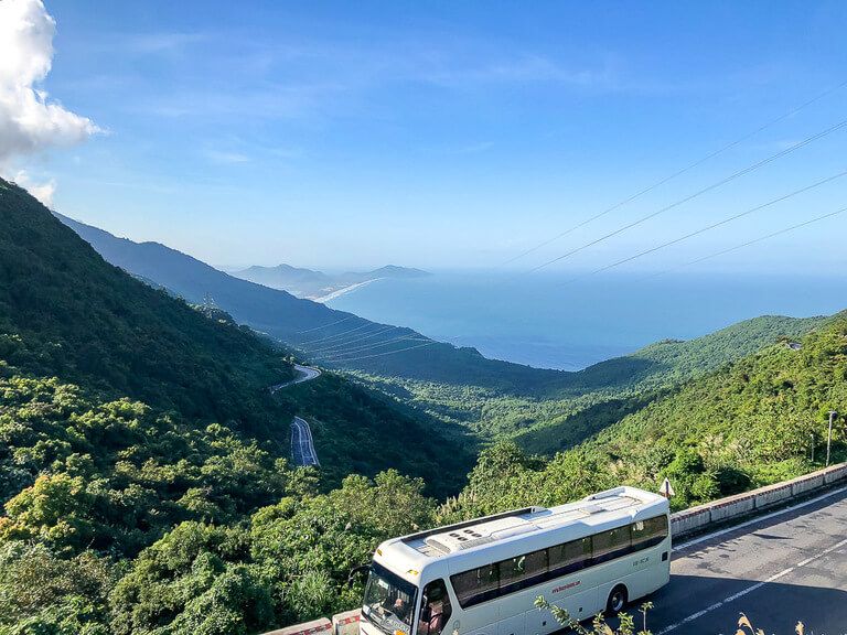 Coach driving up Hai Van pass between hue and da nang green trees and sea behind