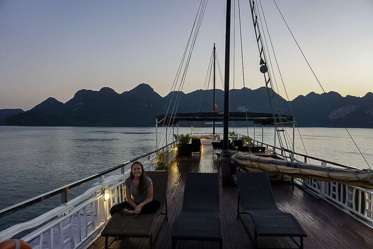 kristen sat on top deck of Rosa Cruise at dusk in Halong Bay