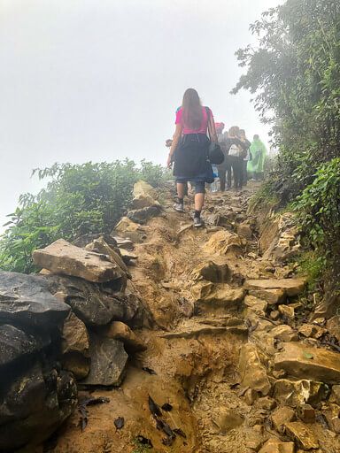 Kristen walking up rocky path in clouds sapa itinerary vietnam
