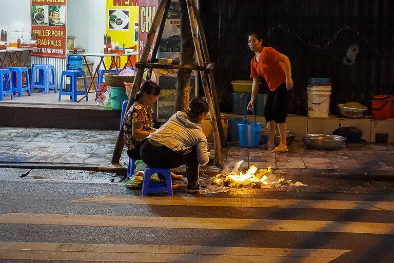 Women cooking food on street in Hanoi flames on ground