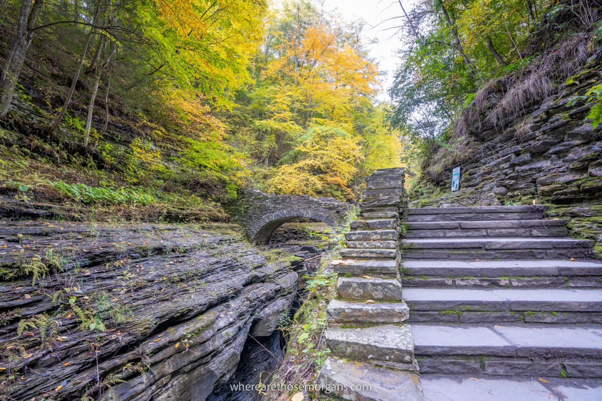Stone stairs leading to the stone Mile Point Bridge backed by colorful leaves