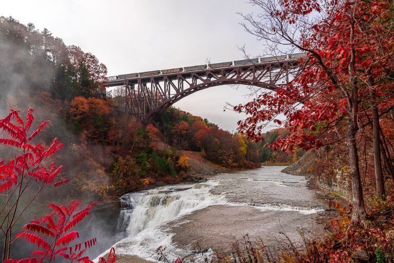 Stunning fall colors around letchworth state park with train crossing steel arches railroad bridge