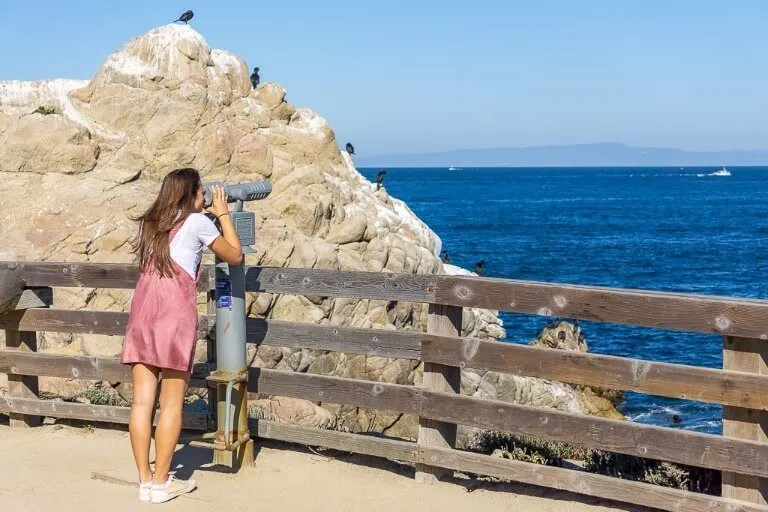 Kristen looking through a telescope near Monterey Bay California when driving San Francisco to San Diego pacific coast highway 1