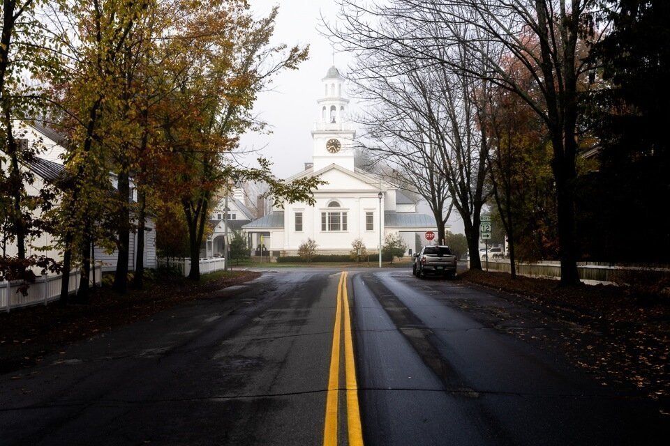 Eerie photo of a white church with dark road leading up in woodstock vermont misty image