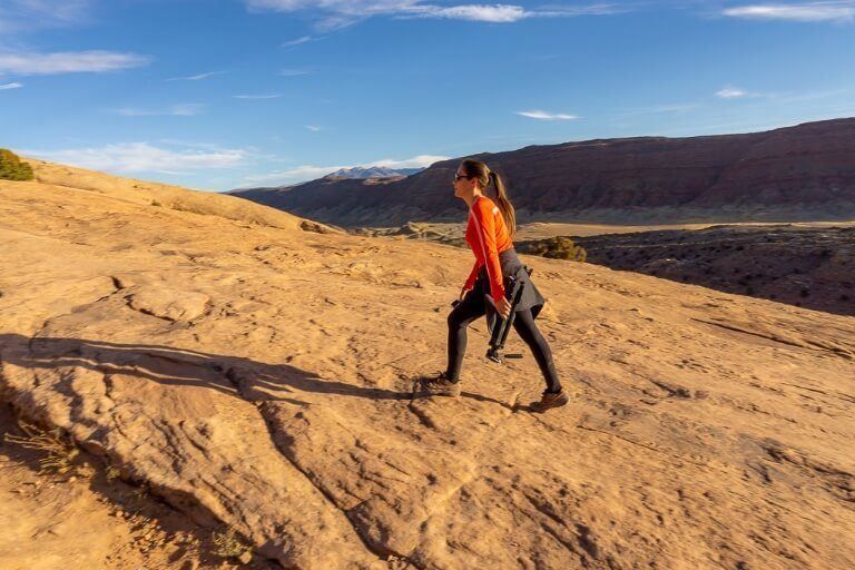 Kristen walking up a slab of rock to Delicate Arch in Utah for sunset