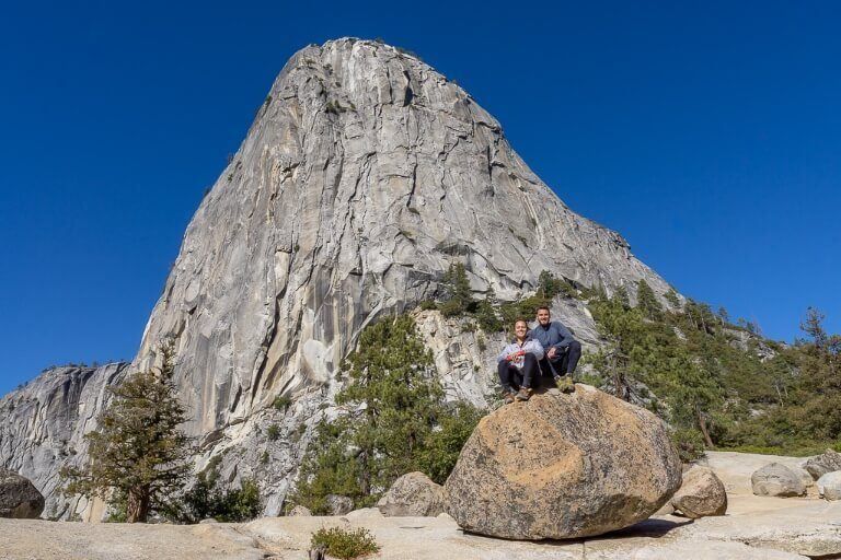 Mark and Kristen sat on a boulder with towering Liberty Cap behind in Yosemite National Park photography from Mist trail
