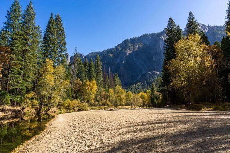 Sandy beach along river with trees and blue sky in stunning valley