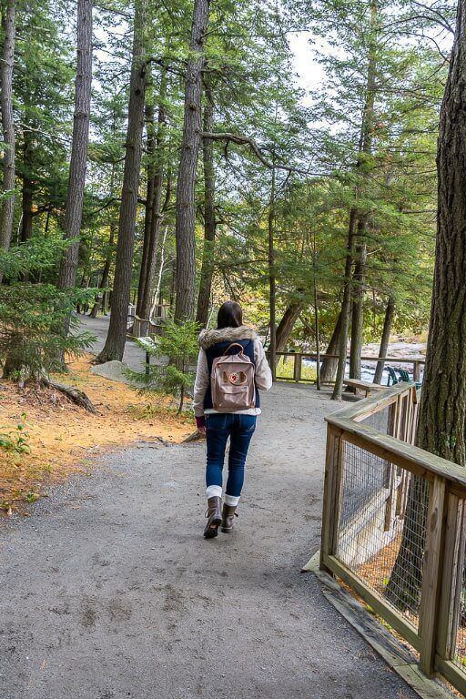 Woman walking through forest on path next to river in new york