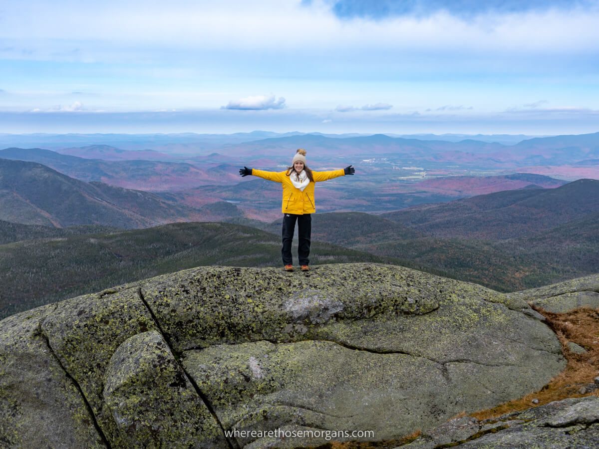 Hiking Mount Marcy in the Adirondacks Mountains New York spectacular views from the summit with woman outstretched arms celebrating climbing the hike to reach the top of the highest high peak Where Are Those Morgans