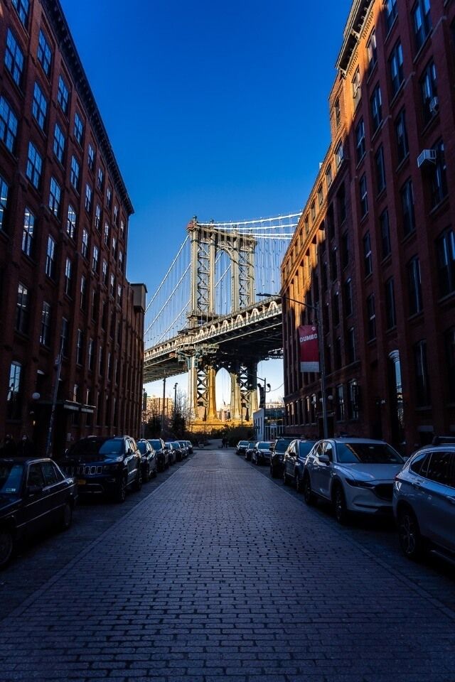 Dumbo Washington Street iconic photograph of Manhattan Bridge at sunrise through narrow buildings clear blue sky one of the best photography locations in NYC