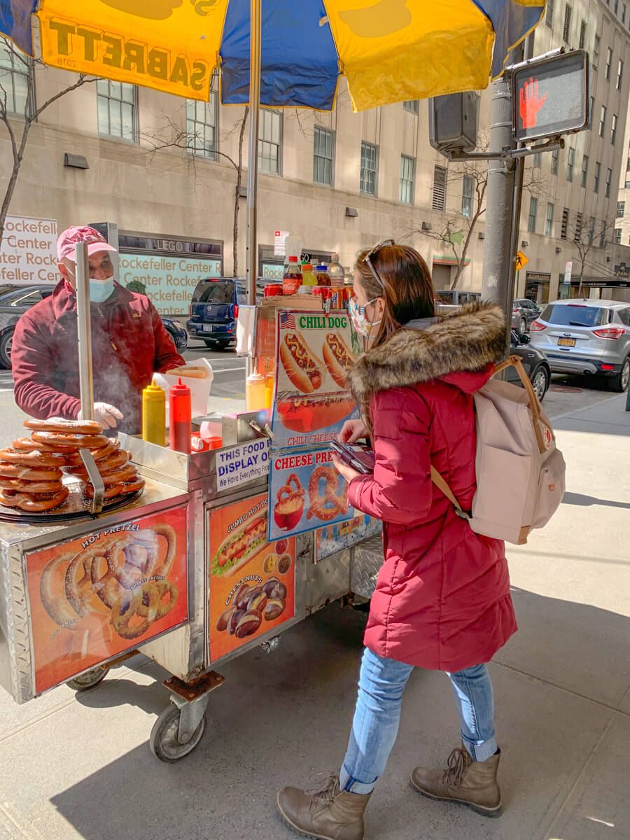 Woman buying hotdog from stand on the street in new york city