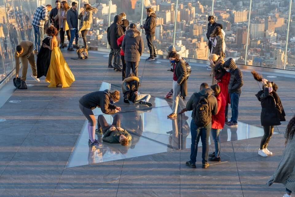 Tourists taking photographs in a glass corner and on a glass bottomed floor in New York City