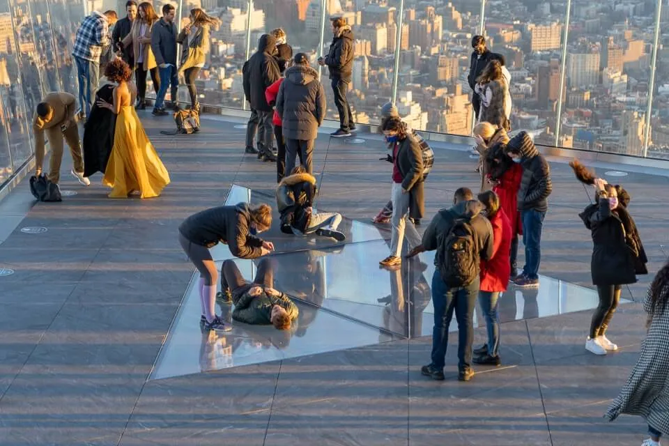 Tourists taking photographs in a glass corner and on a glass bottomed floor in New York City