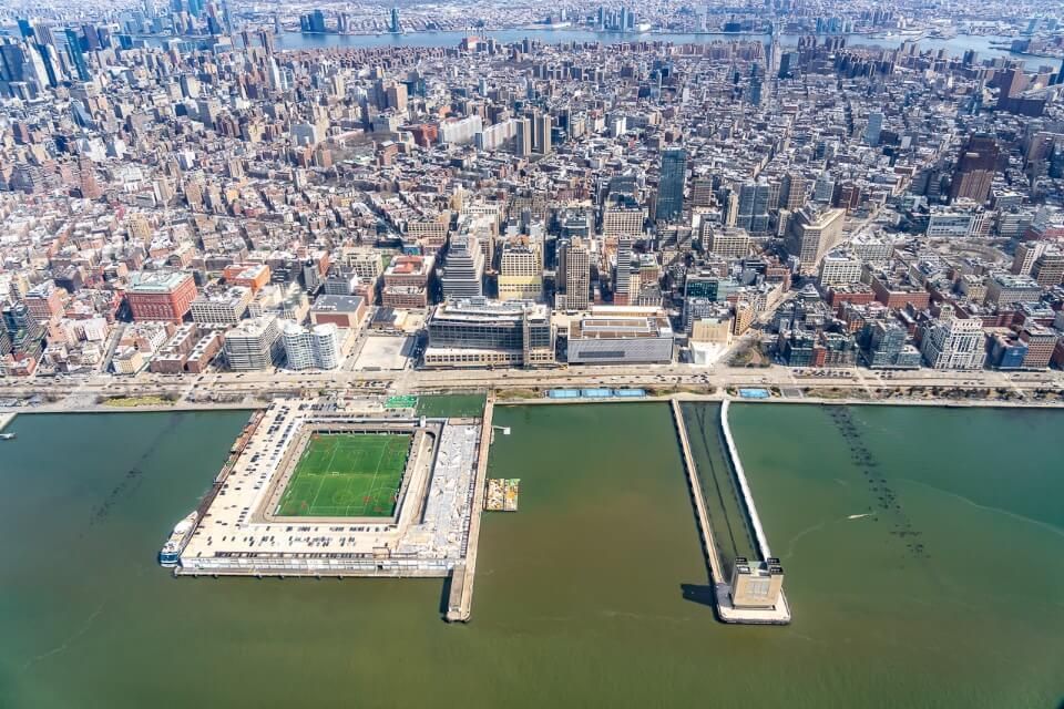 Manhattan skyline with soccer pitch in hudson river and tunnel vent