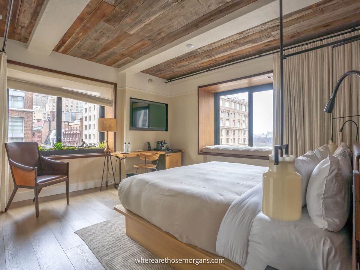 Photo of the inside of a hotel room in NYC with wooden furnishings and light streaming in through windows