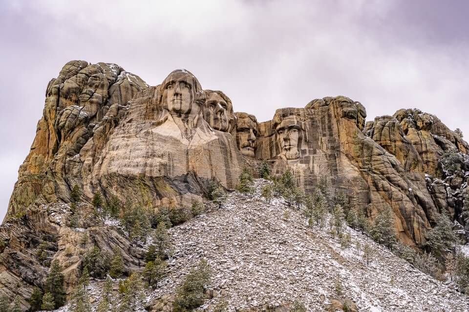 Best places to stay near mount rushmore hotels in keystone and black hills mt rushmore sculpture carved into rock with clouds full of snow