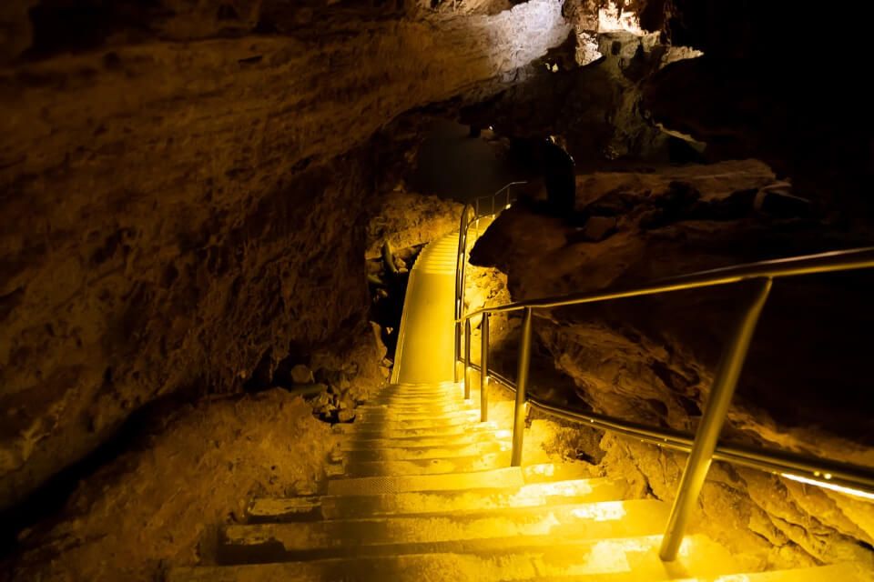 Steps leading down into a cave with yellow light illuminating the path