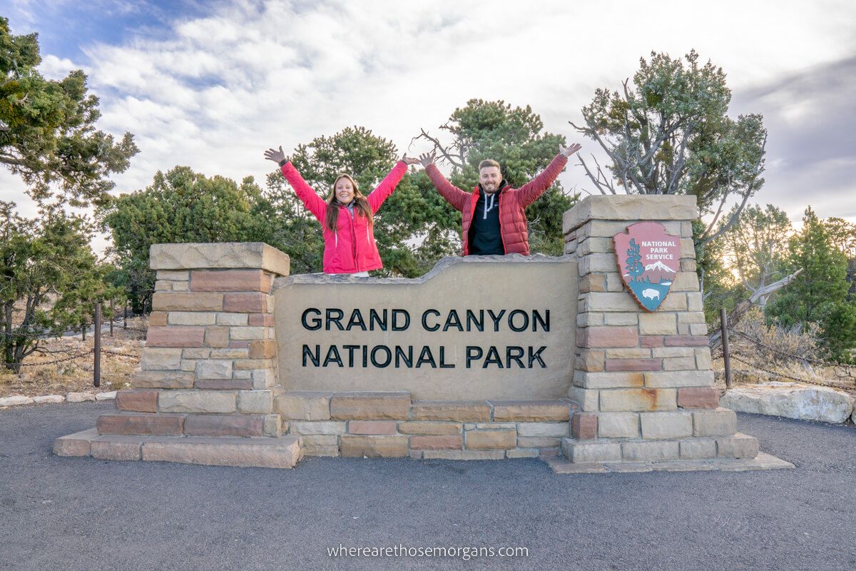 Mark and Kristen Morgan from Where Are Those Morgans at the Grand Canyon national park sign staying in the best hotels near Grand Canyon South Rim