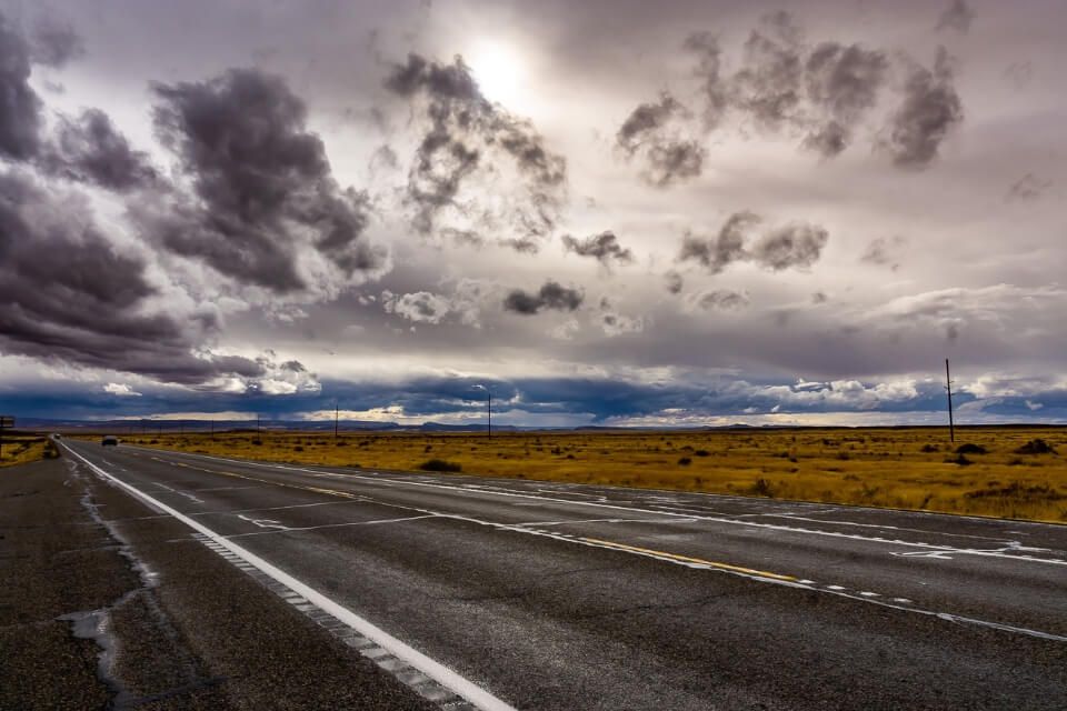 Cloudy sky with sun on a road in utah near arches national park tips on how to plan a road trip