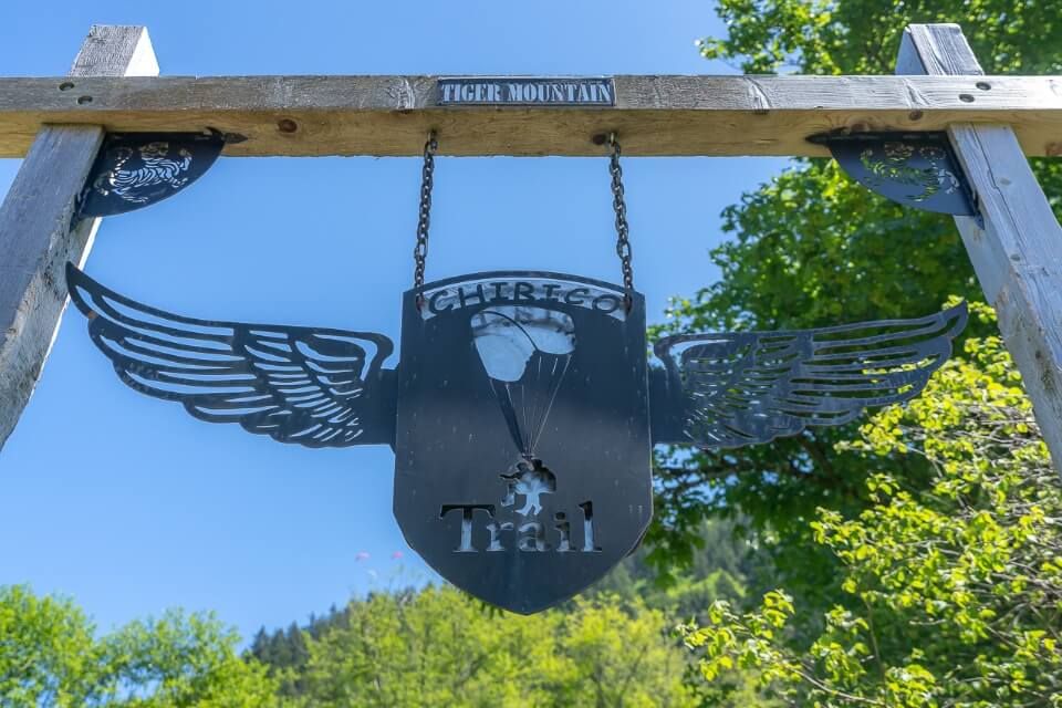 Sign with shield and wings plus parachute marking the beginning of Chirico Trail hike near seattle in washington