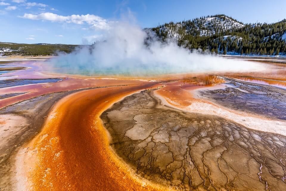 Steam billowing out of grand prismatic spring in april at yellowstone vibrant colors