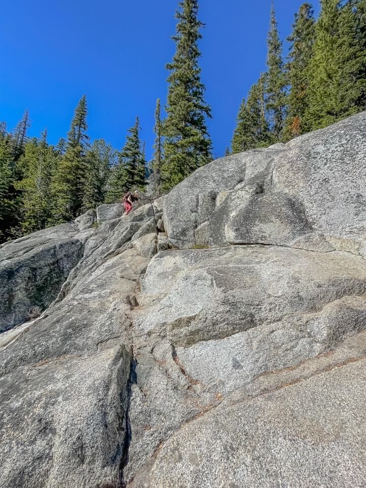 Climbing down steep granite boulder descending to snow lakes from lake viviane