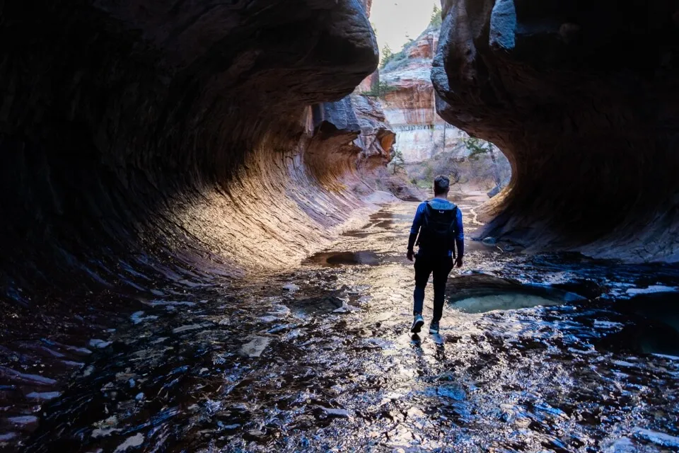 Hiker walking through the Subway in Utah in deep shadows