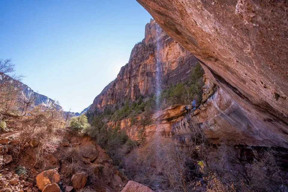 Wispy waterfall flowing from a concave red rock formation