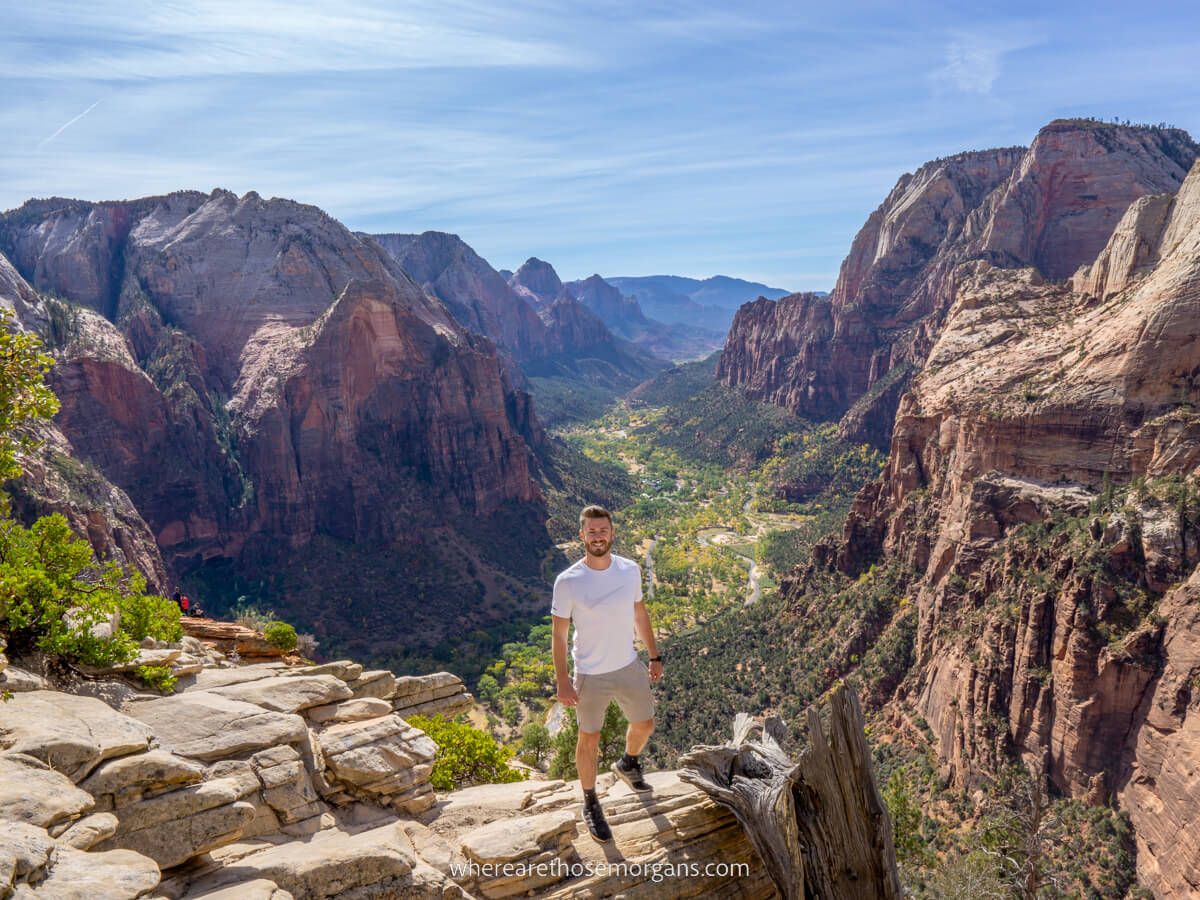 Hiker stood at the top of Angels Landing hike in Zion national park with distant canyon views behind